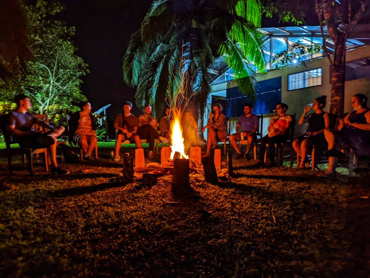 A group of people sat around a campfire at night.