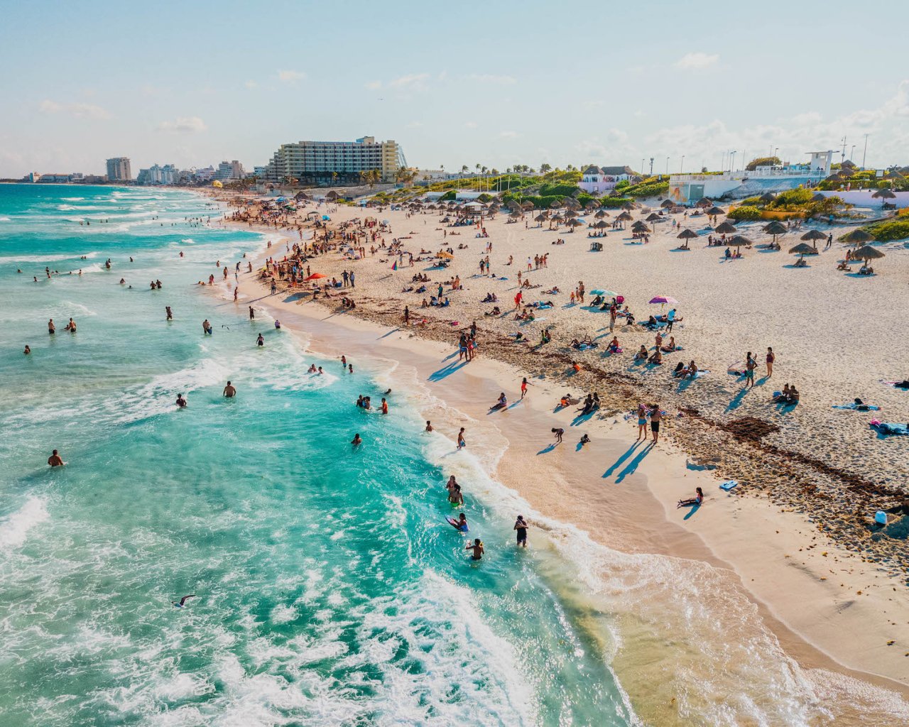 A shot of the beach in Cancun, Mexico, showing people enjoying the white sand and clear blue ocean 